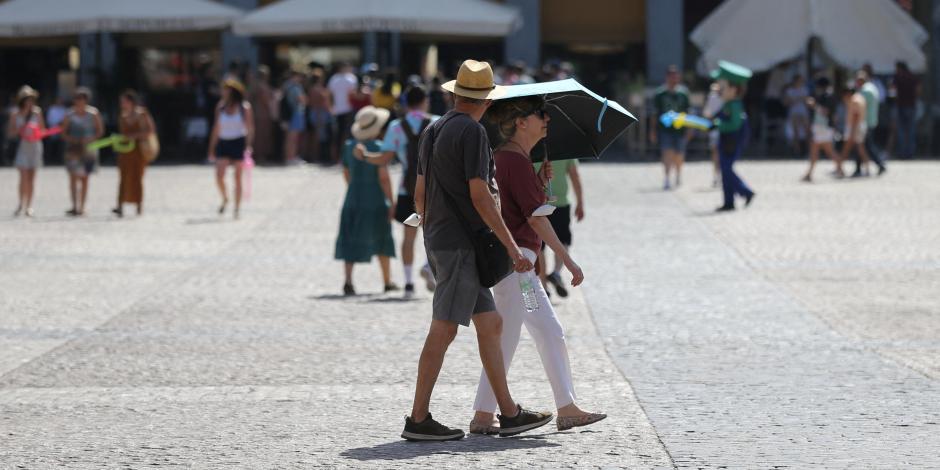 Una pareja se refugia del sol bajo una sombrilla en la Plaza Mayor durante la segunda ola de calor del año en Madrid, España.