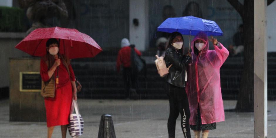 Capitalinos se cubren de las fuertes lluvias en Avenida Reforma, CDMX.