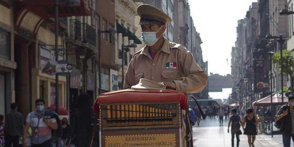 Un organillero utiliza cubrebocas mientras trabaja en la calles del Centro de la CDMX
