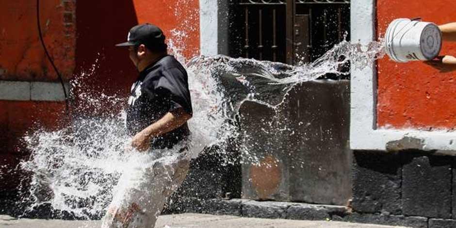 Un hombre recibe un cubetazo de agua en la calle