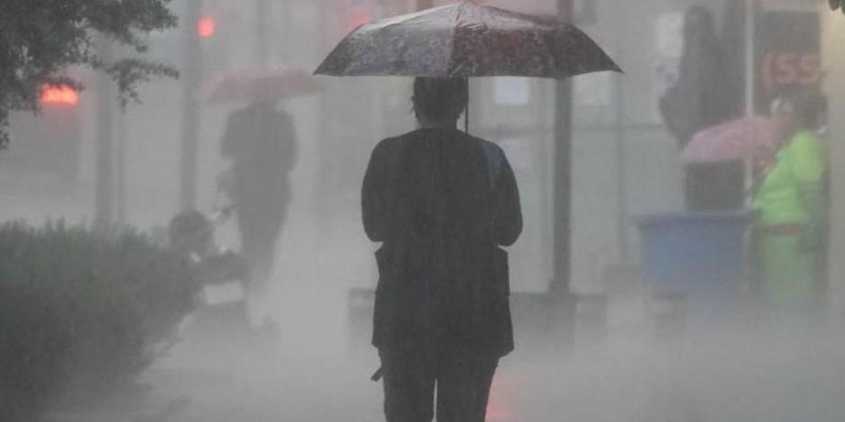 Una persona camina por la calle protegiéndose de la lluvia con un paraguas