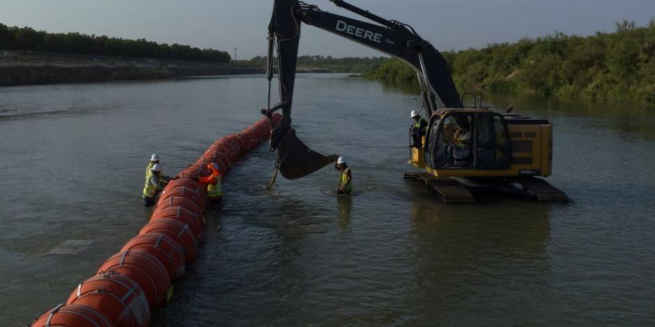 Trabajadores montan una cadena de grandes boyas, para disuadir a los migrantes que cruzan a través del río Grande, en la frontera internacional con México en Eagle Pass, Texas.