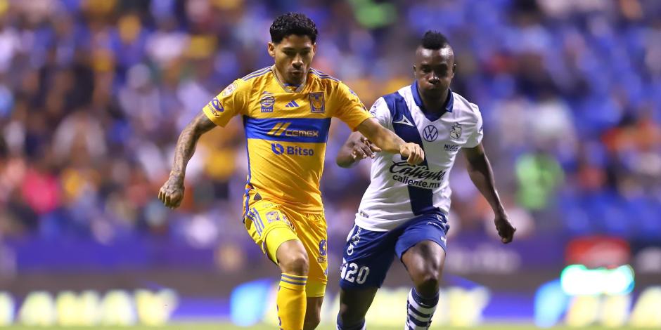 Javier Aquino conduce la esférica ante la marca de Kevin Velasco en la ida de cuartos de final entre Tigres y Puebla.