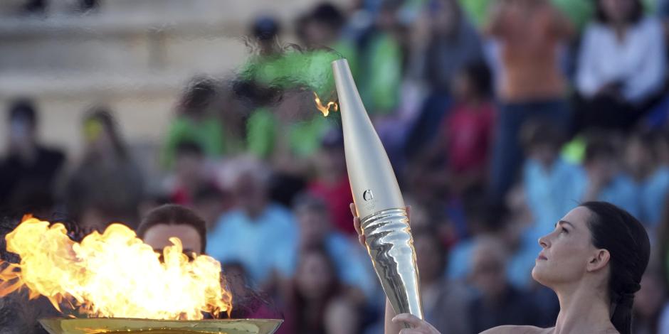 La actriz Mary Mina, como una sacerdotisa griega, sostiene una antorcha con la llama de los Juegos Olímpicos en el Estadio Panatenaico de Atenas