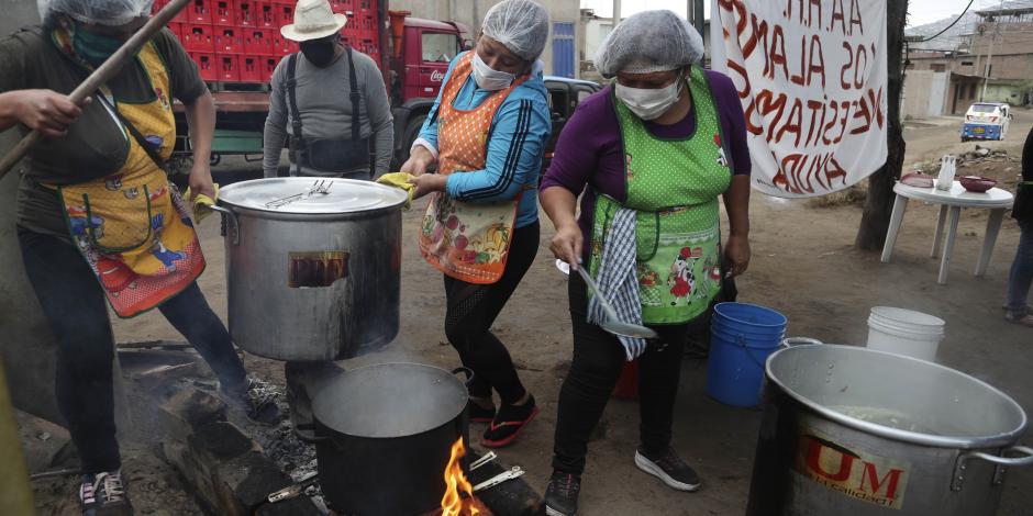 Mujeres preparan comida para un grupo de familias que enfrentan dificultades por la pandemia del COVID-19 en Villa María del Triunfo en Lima, Perú.
