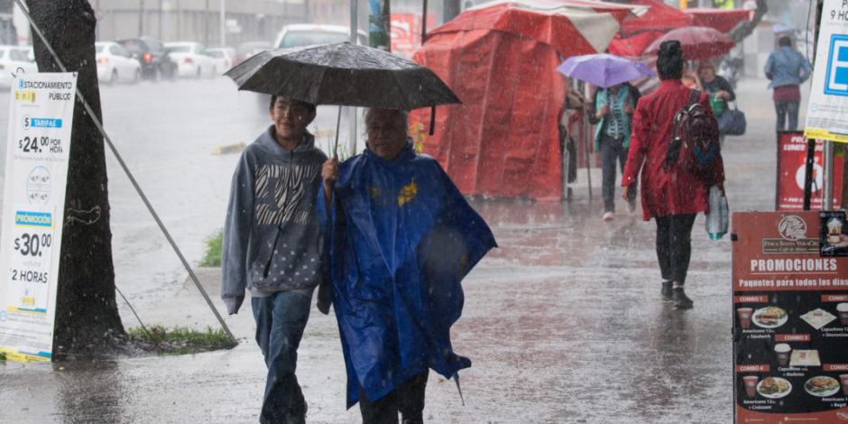 Personas en la calle con paraguas se cubren de la lluvia