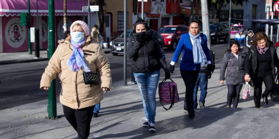 Abrigadas por frío, personas caminan por calles de la CDMX.