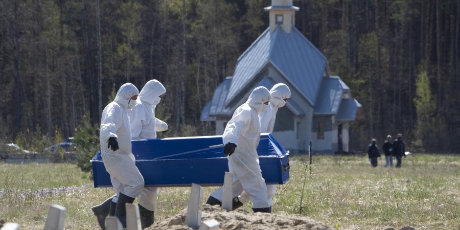 Cavadores de tumbas llevan un ataúd mientras entierran a una víctima de COVID-19 en un cementerio en Kolpino, en San Petersburgo, Rusia, el 10 de mayo de 2020.