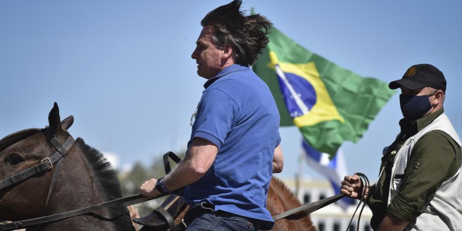 El presidente de Brasil, Jair Bolsonaro, monta un caballo de la policía para saludar a los partidarios reunidos afuera del palacio presidencial en Brasilia, el domingo 31 de mayo de 2020.