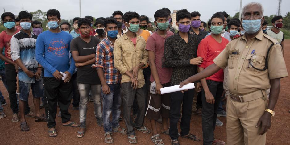 Un agente de seguridad controla una fila de trabajadores migrantes del estado de Bengala Occidental para regresar a sus casas en Kochi, en Kerala,  India el 10 de junio de 2020.
