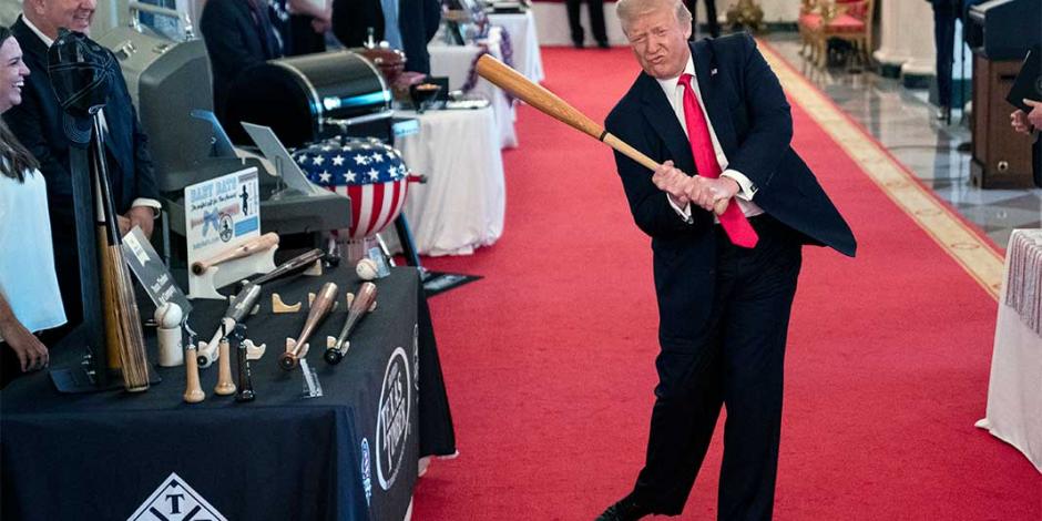 El mandatario agita un bate durante un evento de béisbol en la Casa Blanca, ayer.