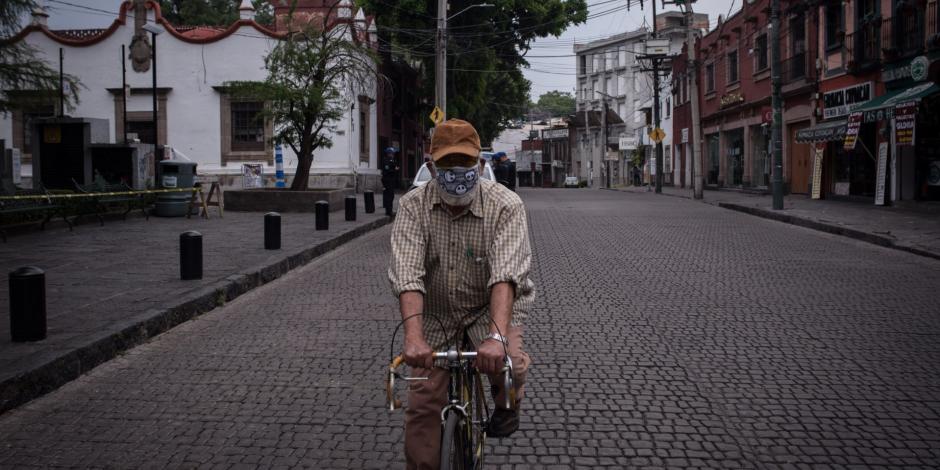 Un hombre circula en bicicleta y con cubrebocas en Coyoacán.
