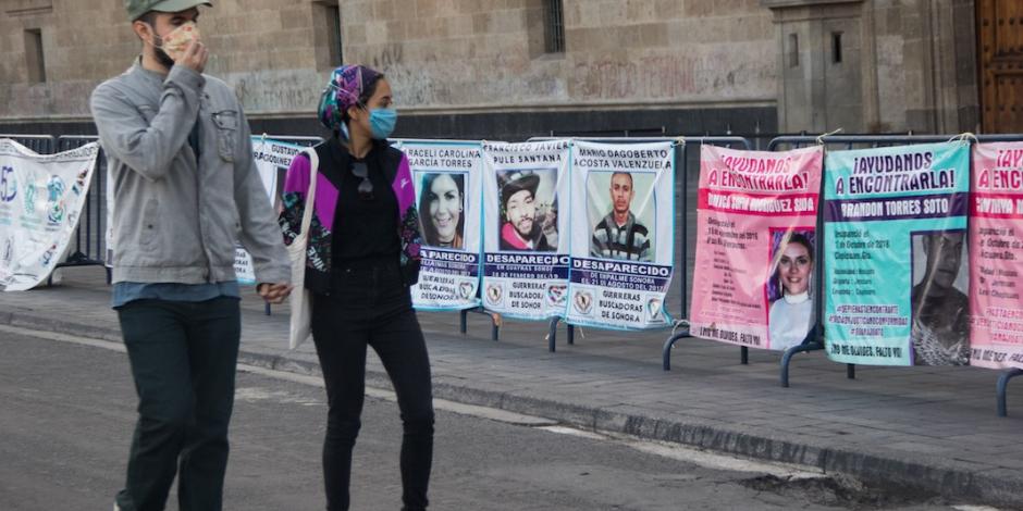 Jóvenes miran retratos de personas no localizadas, en una protesta del 1 de julio.