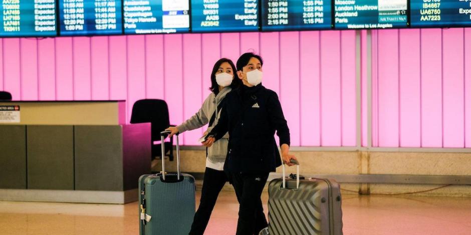Viajeros portando un cubrebocas arriban al aeropuerto de Pekín, ayer.