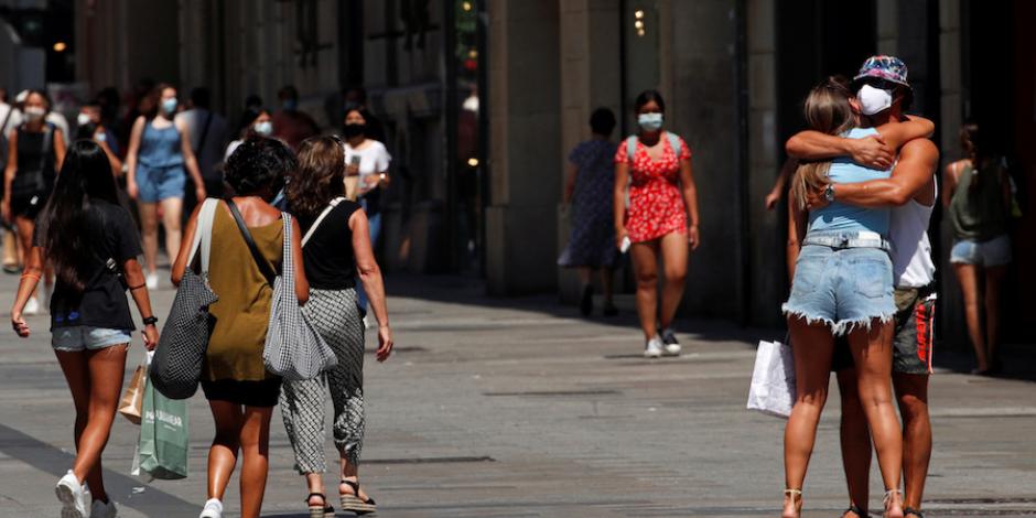 Personas con mascarilla caminan e interactúan en el centro de Barcelona, en Cataluña, ayer.