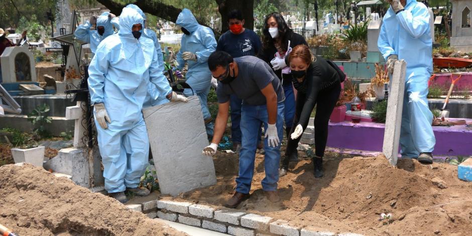 En el panteón de San Nicolás Tolentino, en CDMX, dos personas entierran a su familiar fallecido por coronavirus.