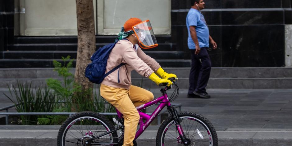 Ciclista se transporta por la avenida Juárez; porta cubrebocas, careta y guantes como medida de prevención de COVID-19.
