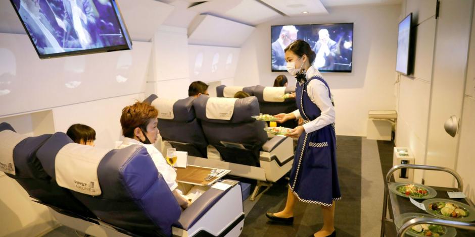 Personal vestido como asistente de vuelo sirve comidas a los clientes de First Airlines, que brinda experiencias de vuelo de realidad virtual.