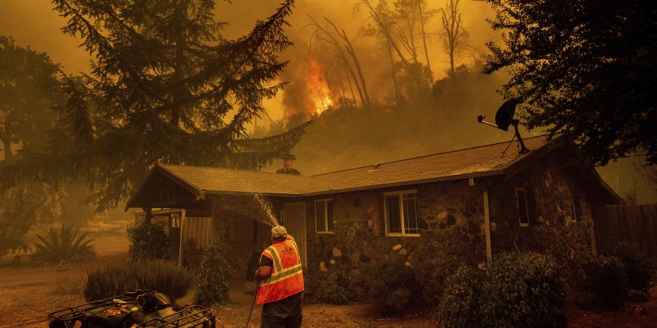 Rocían agua en una casa cuando se acercan las llamas de los incendios, en California, el 18 de agosto de 2020.