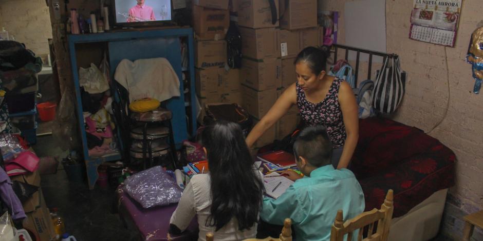 Alondra ayuda a sus hijos Ximena, de tercero de secundaria, y Gustavo, de sexto de primaria, en sus TV clases, ayer en Iztapalapa.