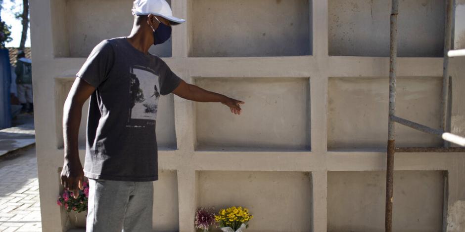 Un hombre señala el nicho de su madre que murió por coronavirus en Buzios, Brasil. .