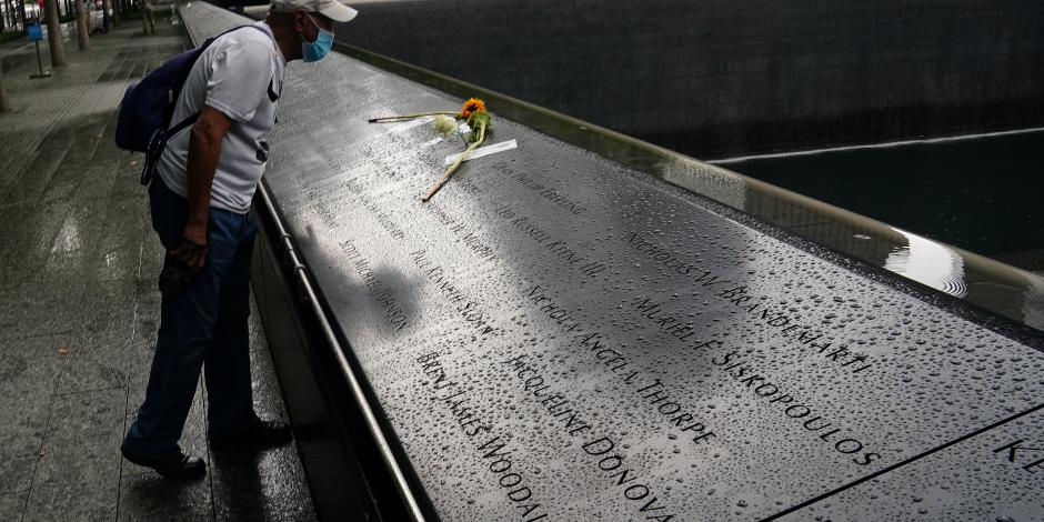 Un hombre observa una flor colocada encima del memorial con los nombres de las víctimas, en Nueva York.