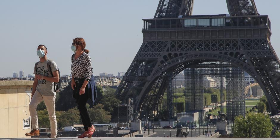 Transeúntes con mascarillas caminan frente a la Torre Eiffel, en Paris, Francia.