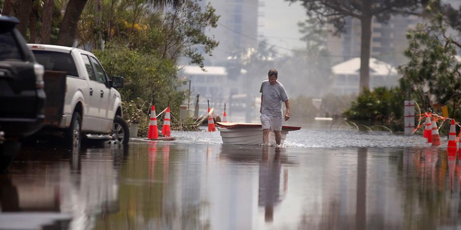Un hombre jala un bote, luego de que su casa quedara destruída, en Florida, ayer.