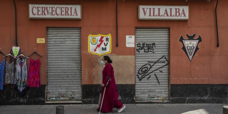 Una residente de Vallecas camina frente a un comercio cerrado en ese barrio, ayer.