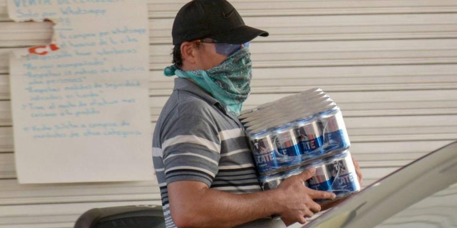 Un consumidor, en la colonia Centro, sale de una tienda con cervezas, en mayo.
