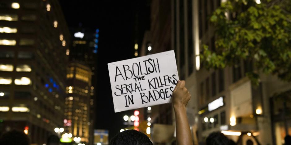Un manifestante muestra una pancarta en la que acusa a quienes portan insignias de ser “asesinos seriales”, el miércoles.