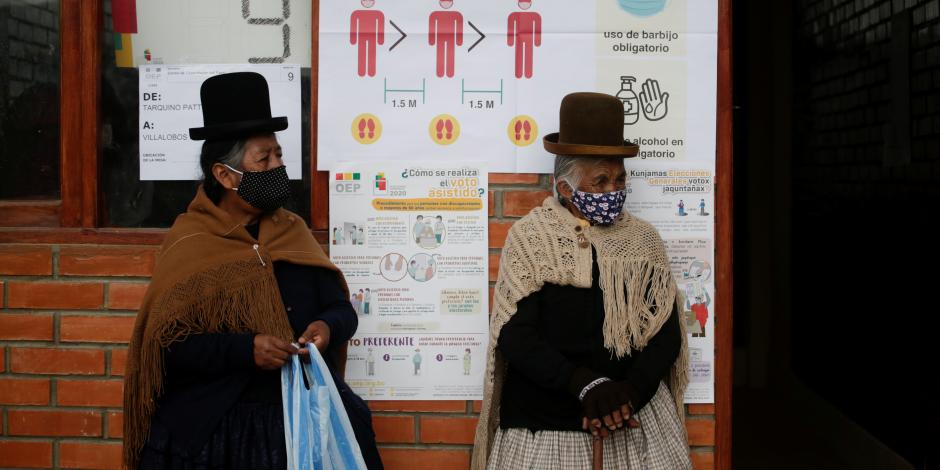 Mujeres con cubrebocas hacen fila en una casilla en La Paz, Bolivia.