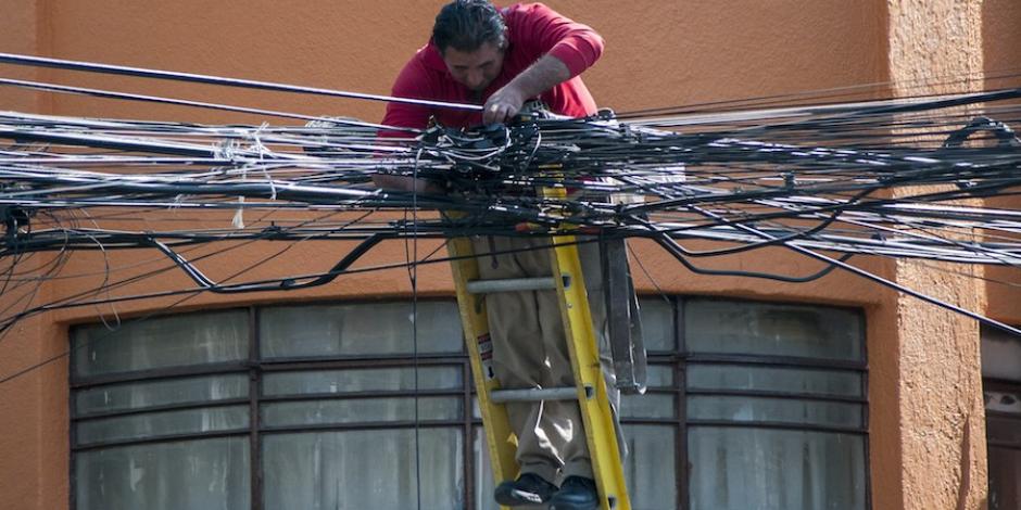 En la imagen de archivo, un empleado de la CFE intenta desenredar cables en una colonia de Azcapotzalco.