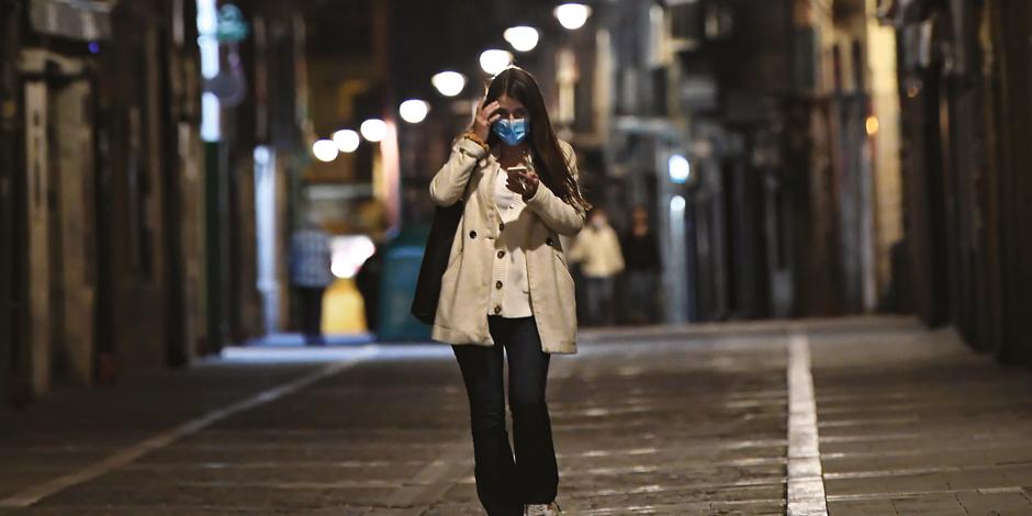Una mujer con cubrebocas camina por una calle vacía de, Pamplona, en  el norte de España, ayer.