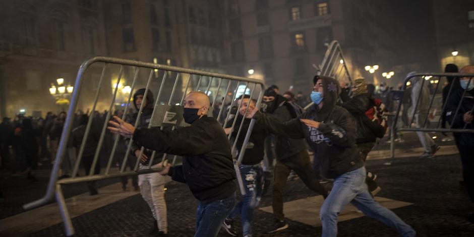 Manifestantes arrojan una valla contra la policía de Barcelona, ayer.
