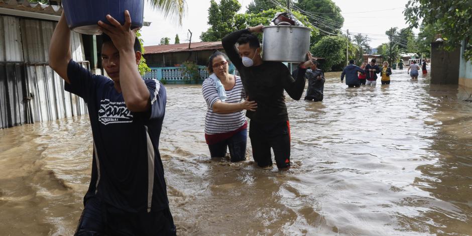 Los residentes caminan a través de las inundaciones cargando sus pertenencias en el vecindario de Suyapa, Honduras, el jueves 5 de noviembre de 2020.