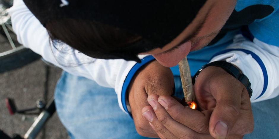 Un joven enciende su cigarro de mariguana en el campamento cannábico apostado frente al Senado.
