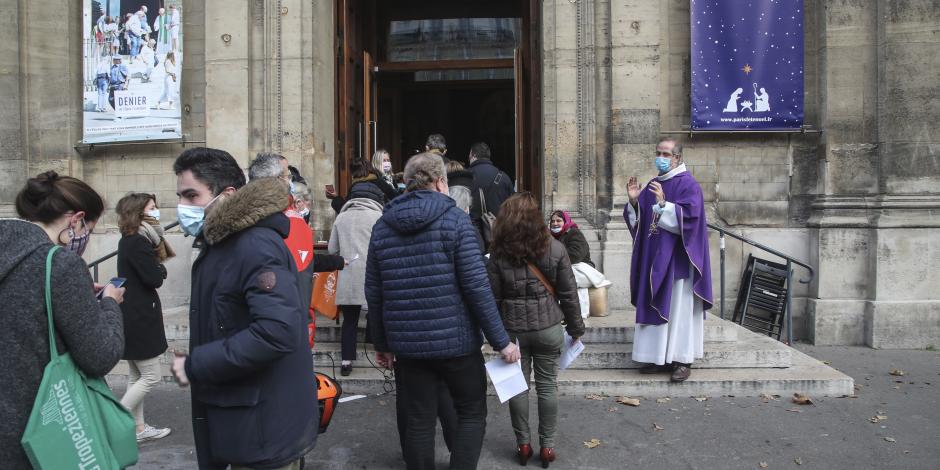 El padre Antoine d'Eudeville (a la derecha) con una mascarilla como precaución contra el coronavirus, recibe a los feligreses mientras hacen fila a la entrada de la iglesia de Notre-Dame-des-Champs en París.
