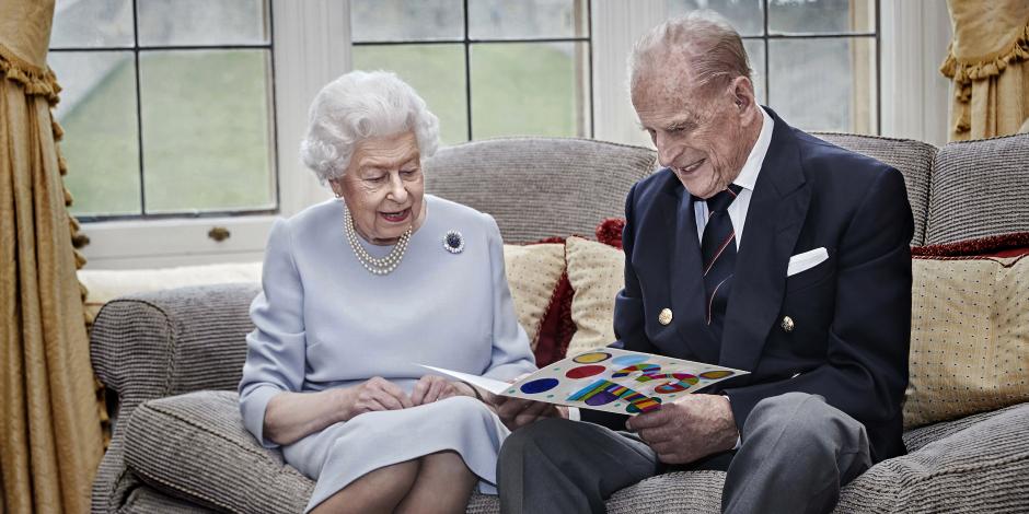En esta imagen difundida el 19 de noviembre de 2020, la reina Isabel II y el príncipe Felipe leen una tarjeta de aniversario de parte de sus bisnietos, en el Castillo de Windsor.