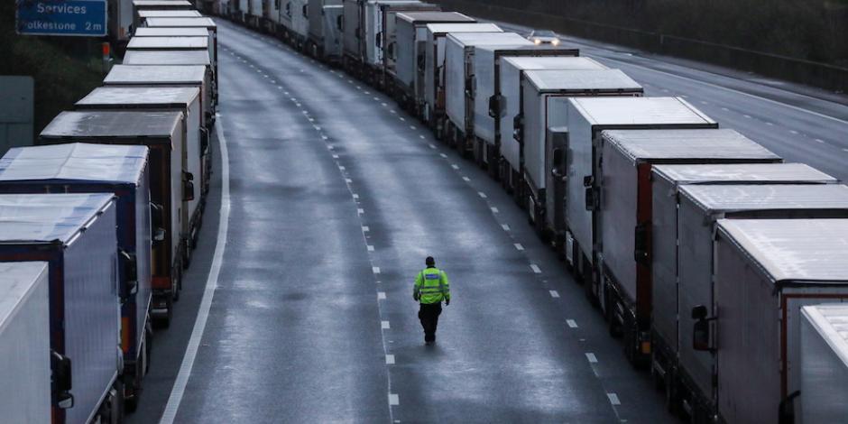 Un hombre camina junto a camiones estacionados en la autopista M20 cerca de Ashford, Gran Bretaña, ayer.