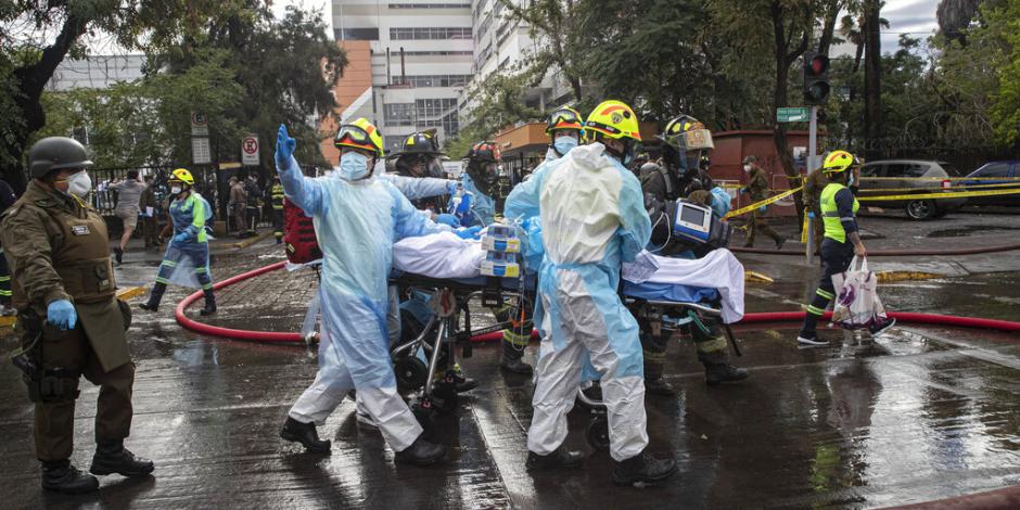 Trabajadores de salud ayudan a evacuar a un paciente con COVID-19 luego de un incendio en el hospital San Borja en Santiago de Chile.