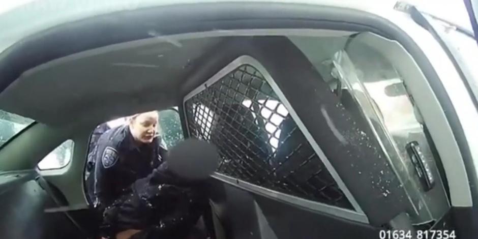Una policía forcejea con la menor afroamericana para subirla a la patrulla.