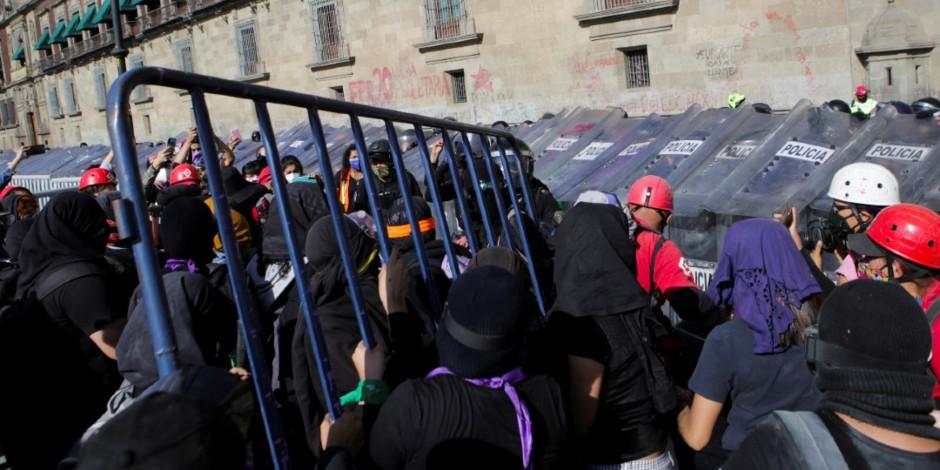 Mujeres quitan valla para intentar pasar a Palacio Nacional.