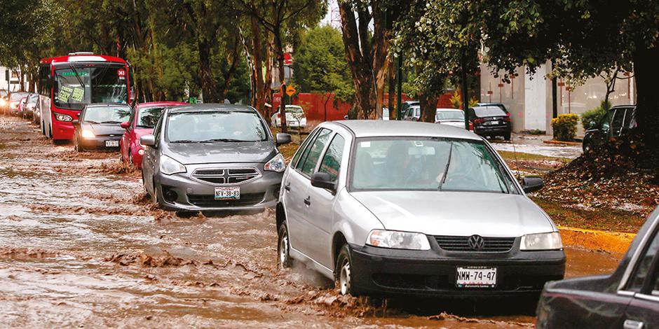 Automóviles transitan en una calle anegada, en el centro de Metepec, ayer.