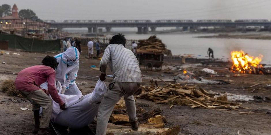 Tres hombres colocan un cuerpo en una pira funeraria a orillas del río Ganges en Uttar Pradesh, la semana pasada.