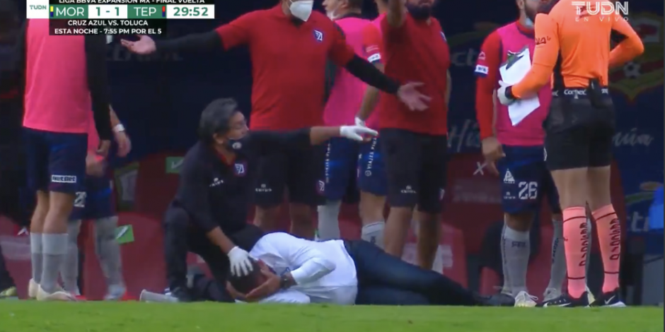 El momento en el que Paco Ramírez, director técnico del Tepatilán FC, queda tendido en el suelo después de que le impactara en la espalda un vaso de cerveza.