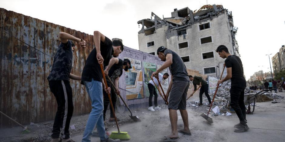 Palestinos limpian los escombros de edificios bombardeados por Israel.
