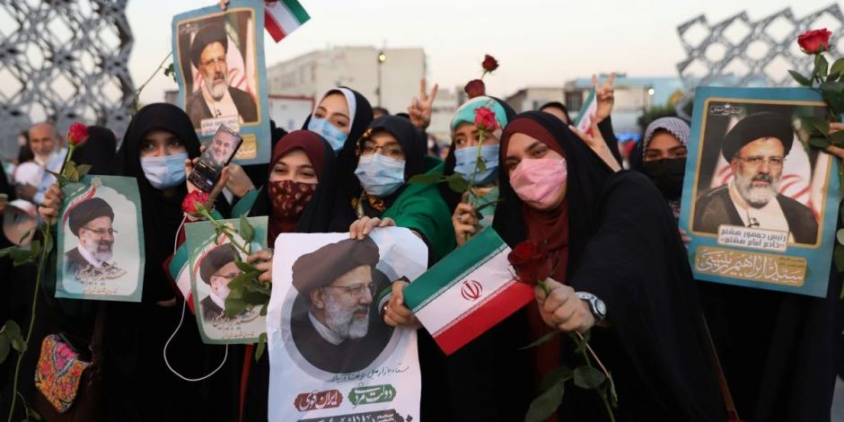 Los seguidores de Ebrahim Raisi sostienen su retrato y rosas, durante una manifestación de celebración por su victoria en las elecciones presidenciales en Teherán, Irán, el 19 de junio de 2021.
