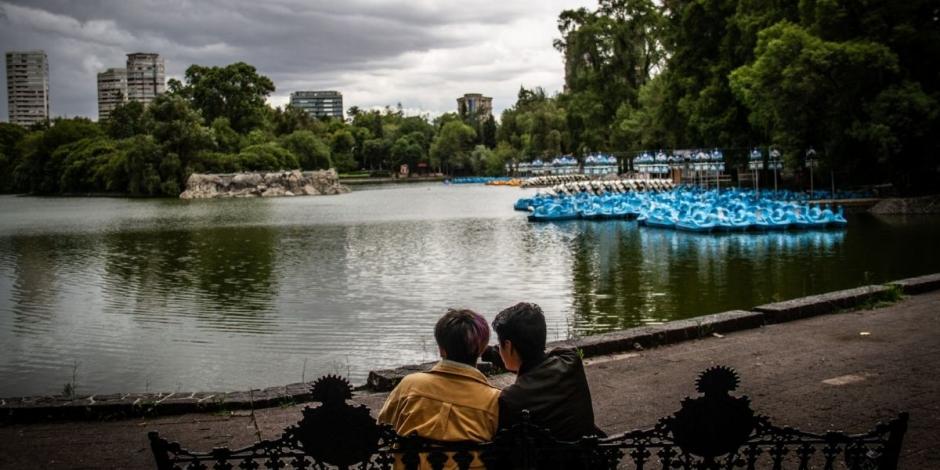 Una pareja descansa frente al lago de Chapultepec.
