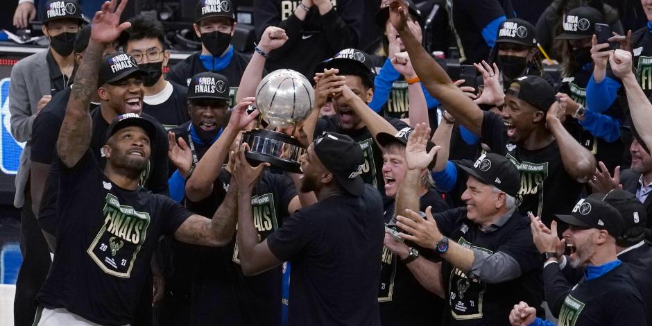 Jugadores de los Bucks celebran con el trofeo que los acredita como campeones de la Conferencia Este de la NBA.